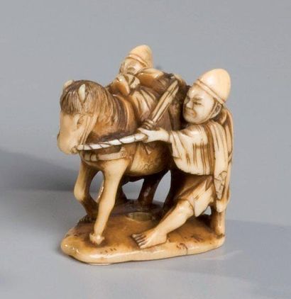 JAPON Netsuke en ivoire représentant deux personnages tentant de retenir un cheval.Signé...