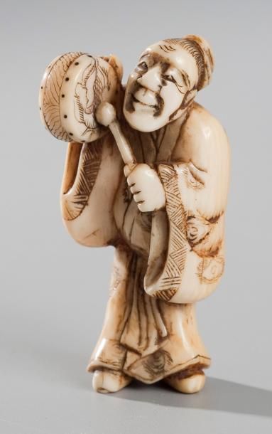null Netsuke en ivoire représentant un homme debout jouant du tambourin. Japon XIXe...