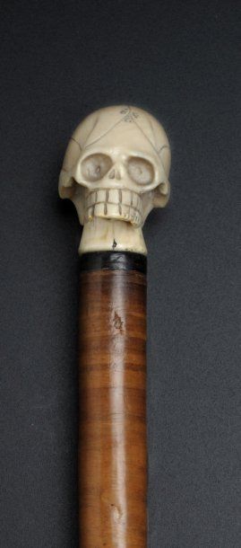 null Badine à pommeau en ivoire sculpté représen­tant un crâne humain. Fût en rondelles...