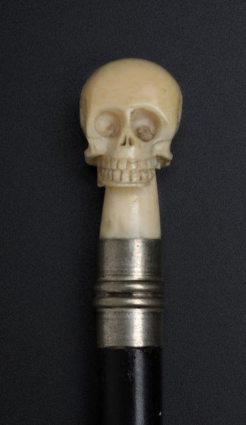 null Badine à pommeau en ivoire sculpté représen­tant un crâne humain. Fût en bois...
