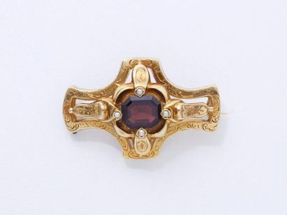 null BROCHE en or 750 millièmes estampé, stylisant une croix ornée d’un grenat taille...