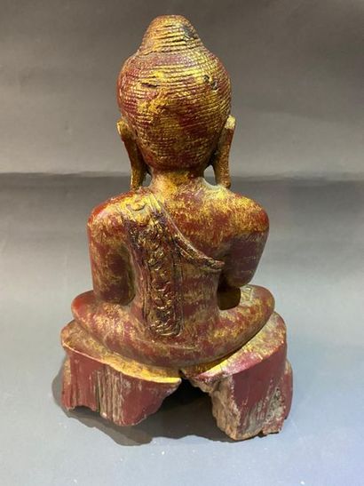 null Bouddha en bois laqué or sur fond rouge, assis en méditation sur une base lotiforme,...