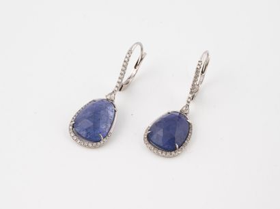 null Pair of white gold sleepers set with a line of diamonds holding a faceted tanzanite...