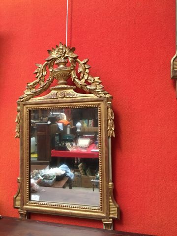 null Miroir en bois et stuc doré rehaussé d'un décor de vase fleuri. Style Louis...