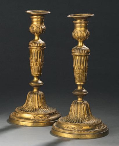 null Pair of gilt bronze torches, the shaft with foliated flutes, resting on a circular...