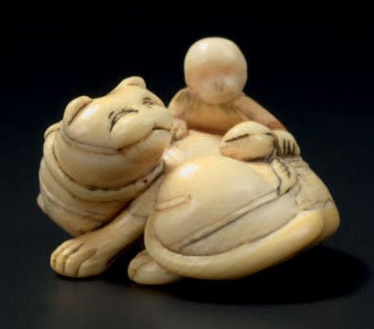 JAPON - XVIIIe siècle 
Netsuke en ivoire, chat allongé jouant avec des rubans tandis...