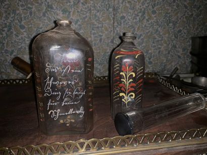  Two polychrome enamelled glass quadrangular bottles, one decorated with an inscription....