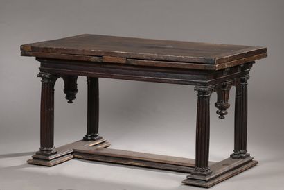 null Italian table in carved walnut of rectangular shape, with two extensions, resting...