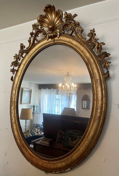 null Important miroir ovale, en bois sculpté et doré, le fronton centré d'une coquille...