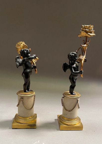 null Pair of gilt bronze, black patina bronze and alabaster candlesticks representing...