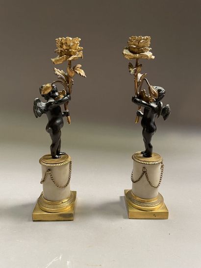 null Pair of gilt bronze, black patina bronze and alabaster candlesticks representing...