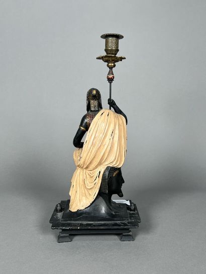 null A painted regula candleholder with a seated Egyptian figure.
Height: 37.5 cm...