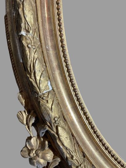 null Oval wood and gilded stucco mirror with laurel leaf motif and ribbon bow pediment....