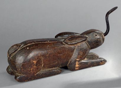 null Bois sculpté représentant un lapin couché tenant dans sa bouche un fer poli...