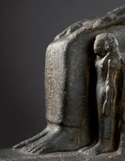  Fragment de statue représentant un homme assis vêtu d'un pagne long, les mains le...