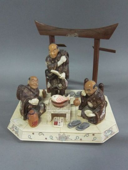 null Okimono en bois et ivoire représentant trois personnages autour d'un déjeuner....