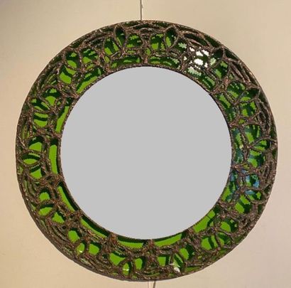  Un miroir rond retro-éclairant sur fond vert. Bronze patiné pour le décor en résille....
