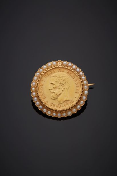  A yellow gold (750‰) circular brooch holding a 20 Lei, Carol I gold (900‰) coin,...