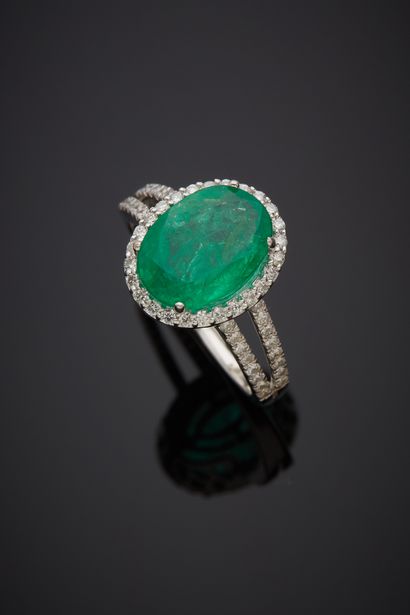 A white gold (750‰) ring set with an oval emerald weighing 3.1 carats, surrounded...