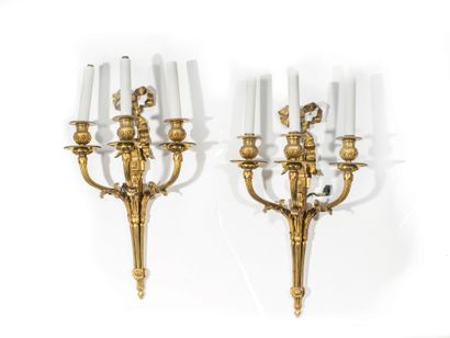  A pair of ormolu three-light sconces with flutes and stylized leaves and a ribbon...