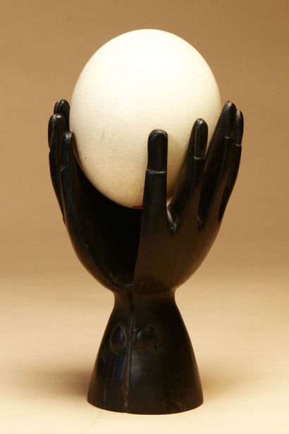 Ostrich egg with wooden stand two hands,...