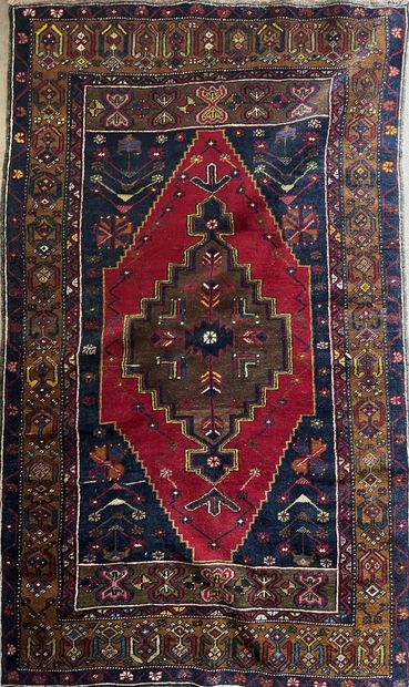 null Oriental wool carpet decorated with a diamond with pendants on a red background,...
