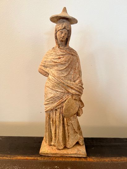 null Terracotta statuette representing a woman wearing a hat and holding a fan. Tanagra...