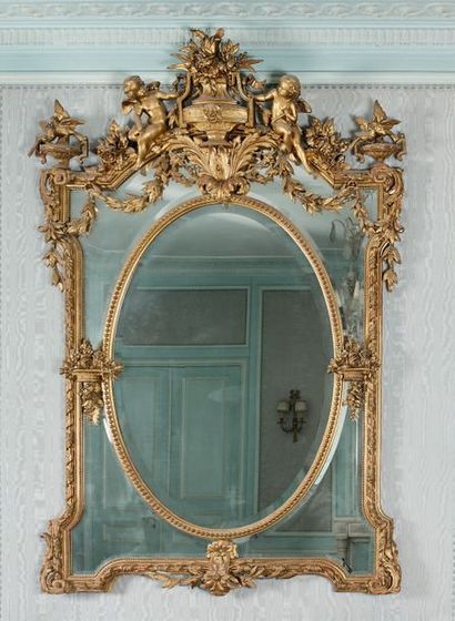  Grand miroir à parcloses en bois et stuc doré, à l'amortisse­ment deux angelots...