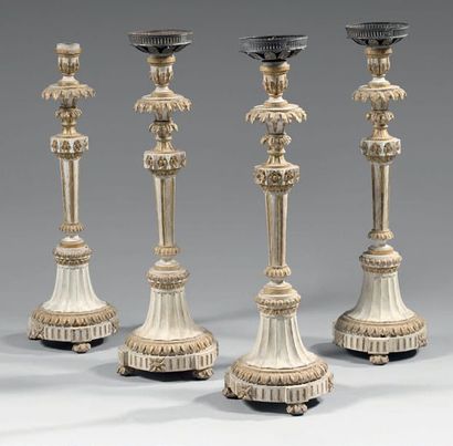 null A series of four carved wooden torches, gilded and white rechampi, foliage bobèches;...