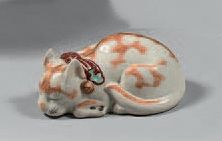 JAPON Figurine en porcelaine représentant un petit chat allon­gé les yeux clos, un...