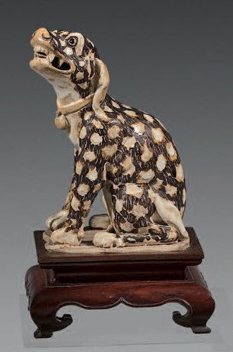 CHINE Figurine en grès représentant un grand chien assis, la robe brune tachetée....