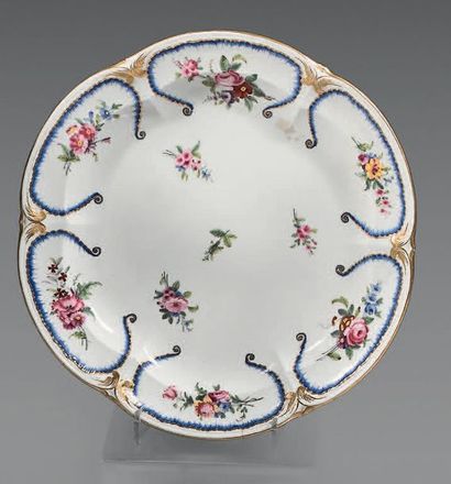 SÈVRES Plat creux en porcelaine de forme circulaire contournée, à décor polychrome...