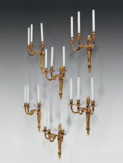 null A suite of six three-light sconces in chased and gilt bronze; the barrels topped...