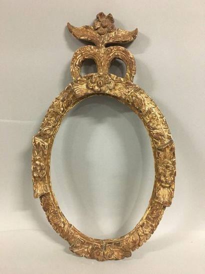 null Oval frame in carved and formerly gilded wood with a frieze of foliage and flower...