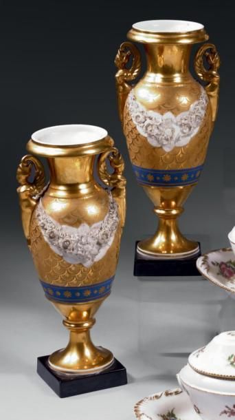 PARIS Paire de vases fuseaux dorés sur piédouche, à deux anses formées de bustes...