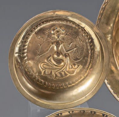 null An embossed brass offering basin decorated with a woman holding a flowering...