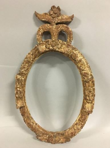null Oval frame in carved and formerly gilded wood with a frieze of foliage and flower...