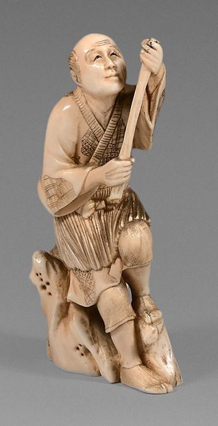 JAPON An ivory Okimono of a fisherman sitting on a rock holding his rod with both...