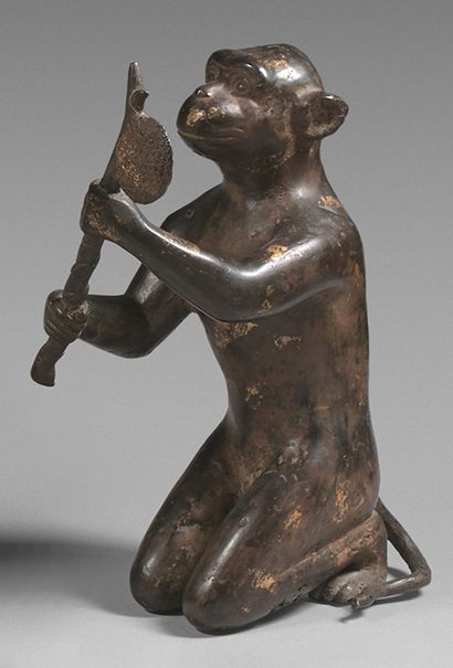 CHINE Large kneeling monkey in bronze with traces of gilding, holding a branch with...