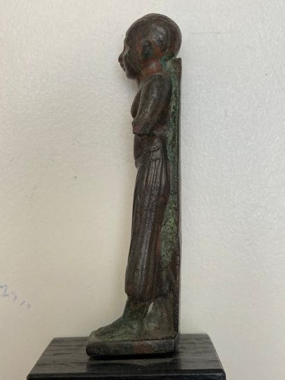  Statuette de prêtre debout marchant. Il porte un pagne long plissé. Bronze à patine...