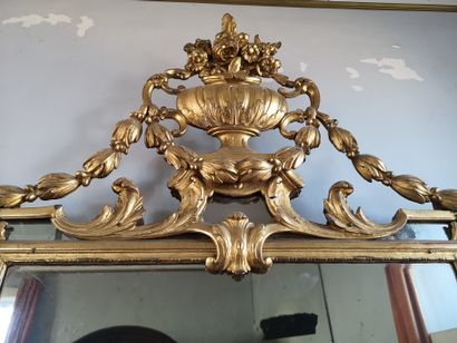 null Gilded mirror with pediment decorated with flowering vase and leafy garlands....