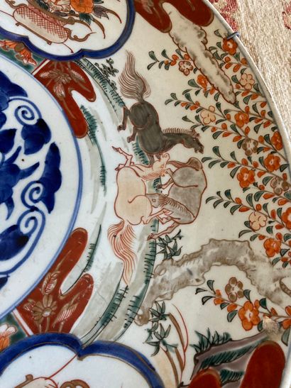null Japon, un grand plat en porcelaine dans la palette imari à décor de chevaux....