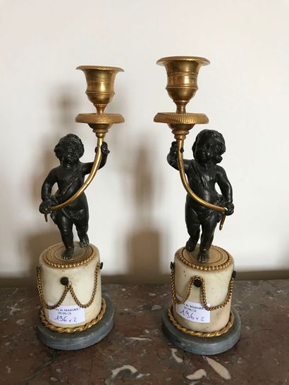 null A pair of ormolu and patinated torches, decorated with a couple of putti on...