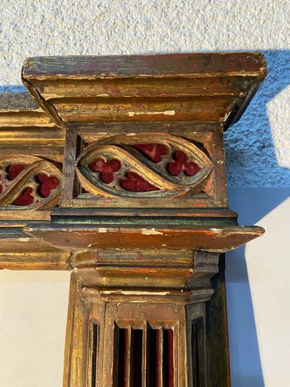  Cadre en bois sculpté à décor architecturé et ajouré sur fond rouge d'esprit néo-gothique...