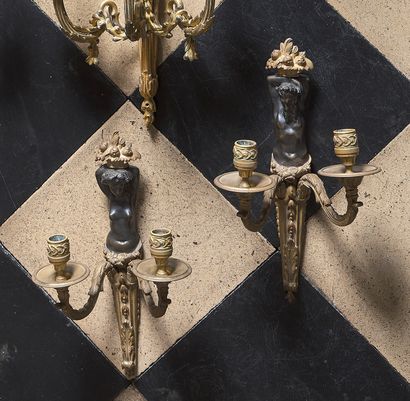 null Pair of two lights sconces in chased, gilt and patinated bronze, decorated with...