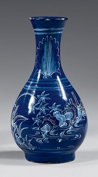 NEVERS Petit vase de forme balustre en faïence à fond bleu persan, décoré en blanc...