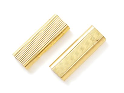 null CARTIER. Lot in gilt metal, consisting of 2 gas lighters with grooved decoration...