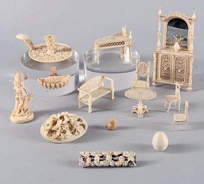 null Lot of fourteen finely carved or beaded ivory curios, including a candlestick...