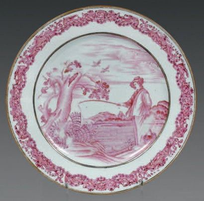 null CHINE DE COMMANDE. Assiette ronde à décor en camaïeu rose représentant un pêcheur...