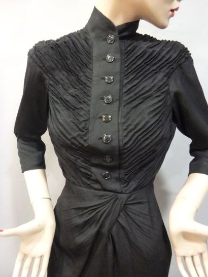  Robe d'hôtesse, Jacques FATH, vers 1939. Crêpe de soie noir. Corsage plissé boutonné...